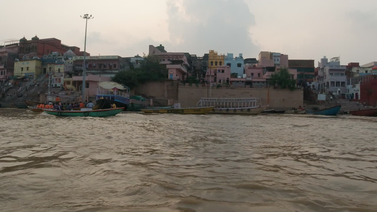 cinematográfica puesta de sol antigua ciudad santa varanasi india río ganges la gente se reunió en un crucero en barco por el canal del estado norte la gente en la provincia de ghat pradesh el paisaje gris nublado a la derecha seguir la cámara lenta a la derecha