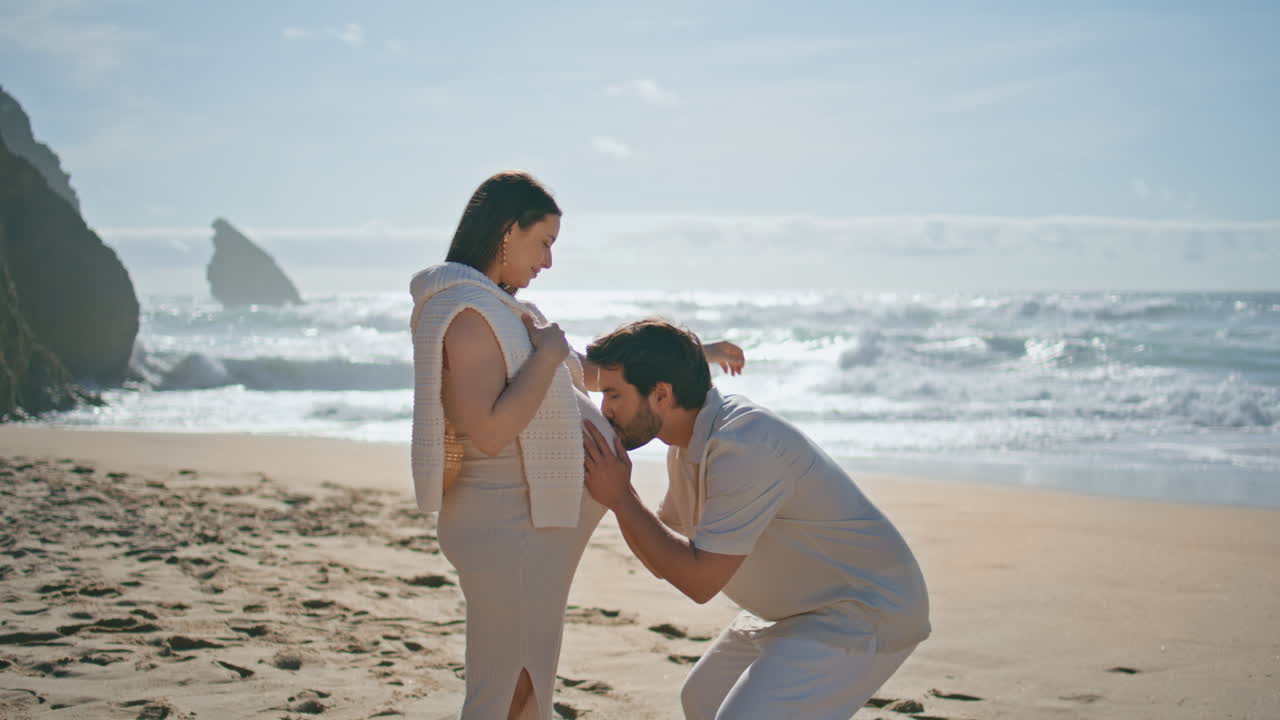 임신 한 커플이 해변에 서있는 은 날. 사랑 하는 남편이 큰 여자 배를 키스