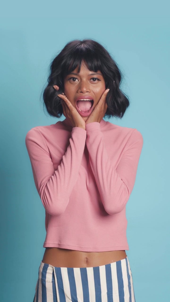 Surprised african american female expressing shock and joy on solid blue studio