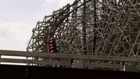 dollywood visitors enjoy the thrills of speed, turns, drops and sudden stop on the lightning rod roller coaster. wooden roller coaster with train moving on track and riders in cars.