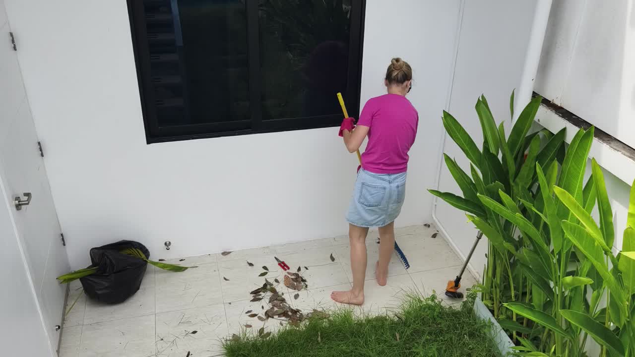 mujer barriendo hojas en el patio