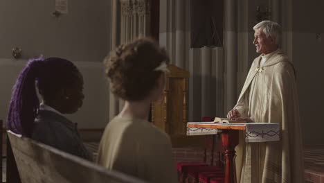 old caucasian clergyman talking to parishioners in christian church