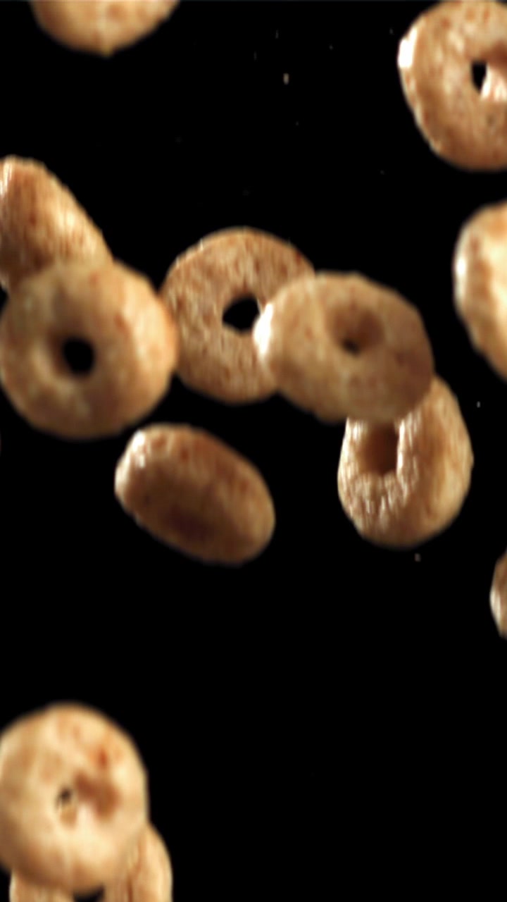 Cereali dorati per la colazione che cadono al rallentatore su sfondo nero