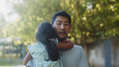 young asian bearded man carrying his little girl in arms