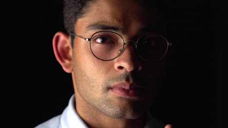 serious portrait of a young man wearing eyeglasses looking in front of camera