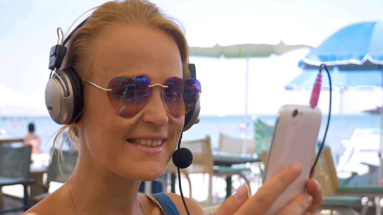 Primo piano di una giovane donna con le cuffie che parla al telefono