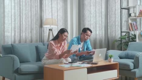 asian couple with a laptop looking at the bill and having headache due to financial problem