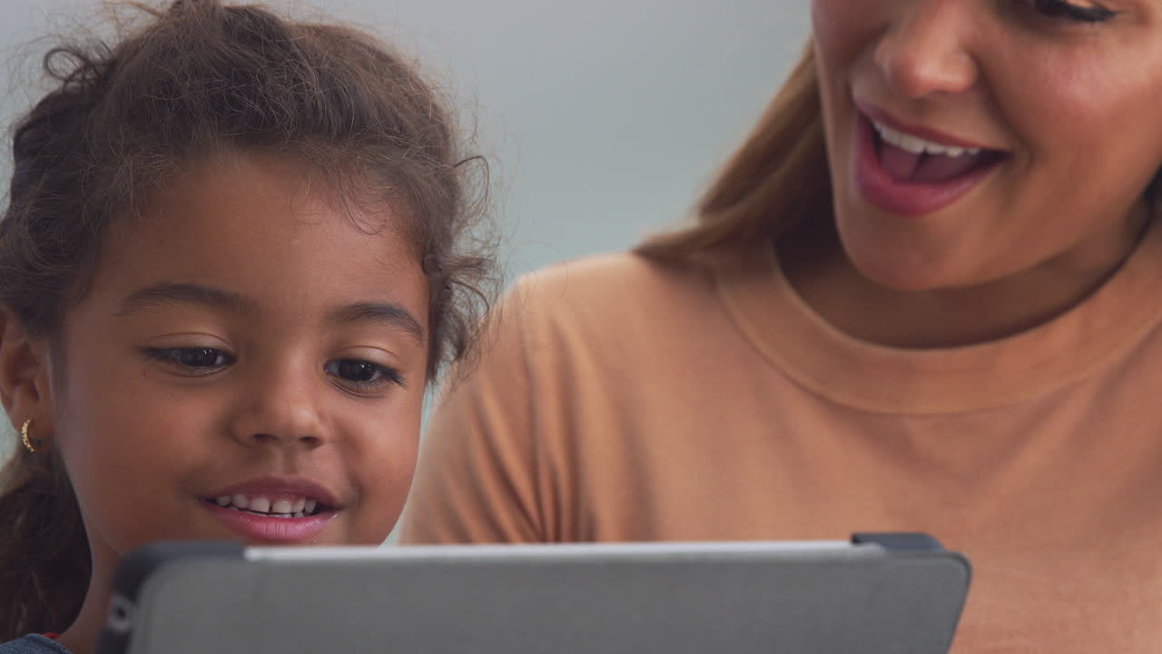 madre hispana ayudando a su hija a la escuela en casa y hacer la tarea con una tableta digital
