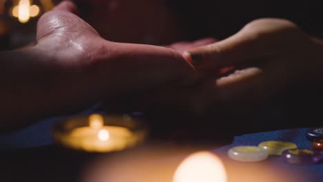 close up of woman reading man's palm on candlelit table 2