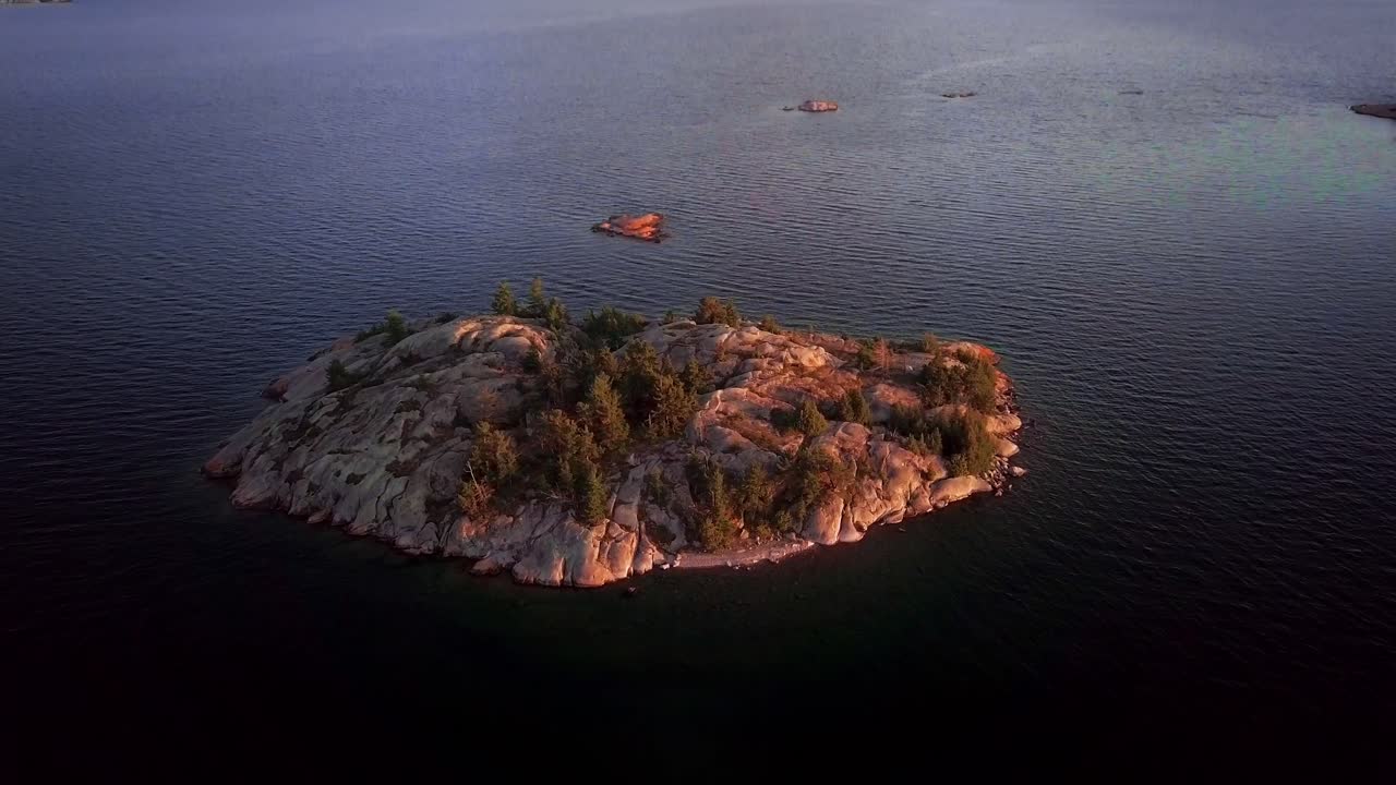 isla de roca blanca con pinos en un gran lago azul, antena de drones con gran inclinación hacia arriba