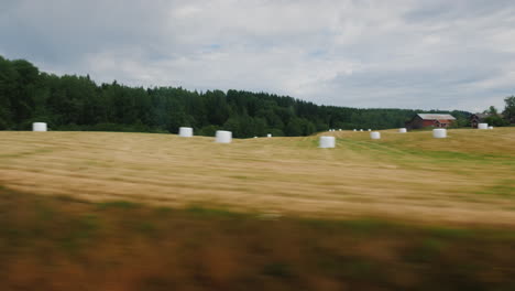 blick aus dem fenster auf die landwirtschaftlichen flächen norwegens, wo heu gemäht und im heuhaufen liegend beau