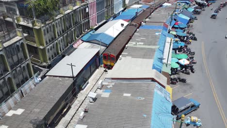 a drone shooting following a train and over the mae klong railway market market