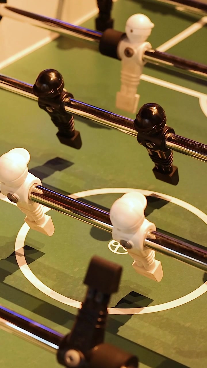Et vertikalt nærbilde av svarte og hvite bordfotballfigurer som spinner på metallstenger.