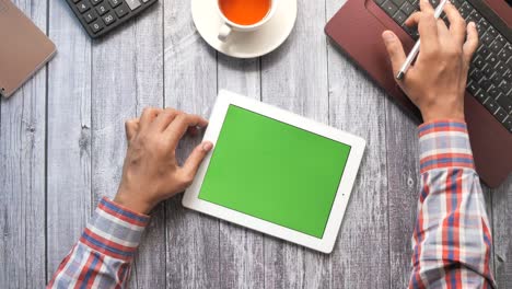 persona que utiliza una tableta y una computadora portátil en el escritorio