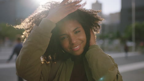 portrait of beautiful trendy african american woman smiling cheerful holding hair enjoying windy urban city at sunset stylish female having fun