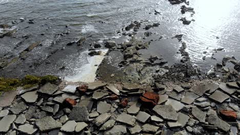 aerial view of stones in the sea with waves crashing on the pier, montevideo, uruguay