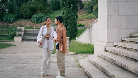 Business-people-talking-park-vertical.-Focused-man-woman-couple-discussing-work