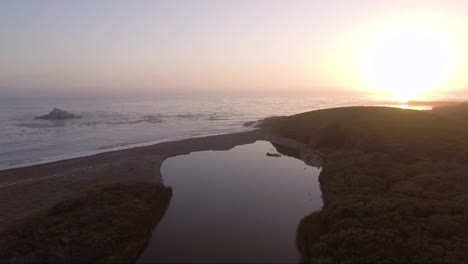 AERIAL---Creek-ends-just-before-ocean-at-sunset