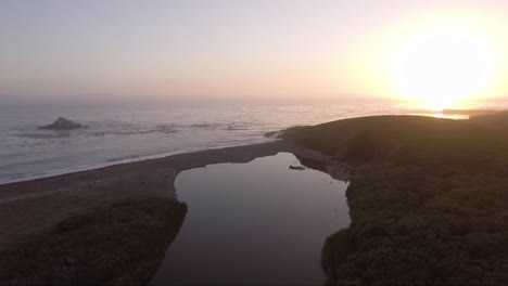 aerial - creek ends just before ocean at sunset