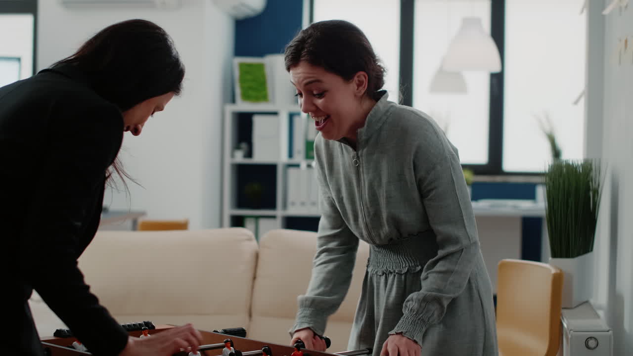 Group of workmates playing game on foosball table