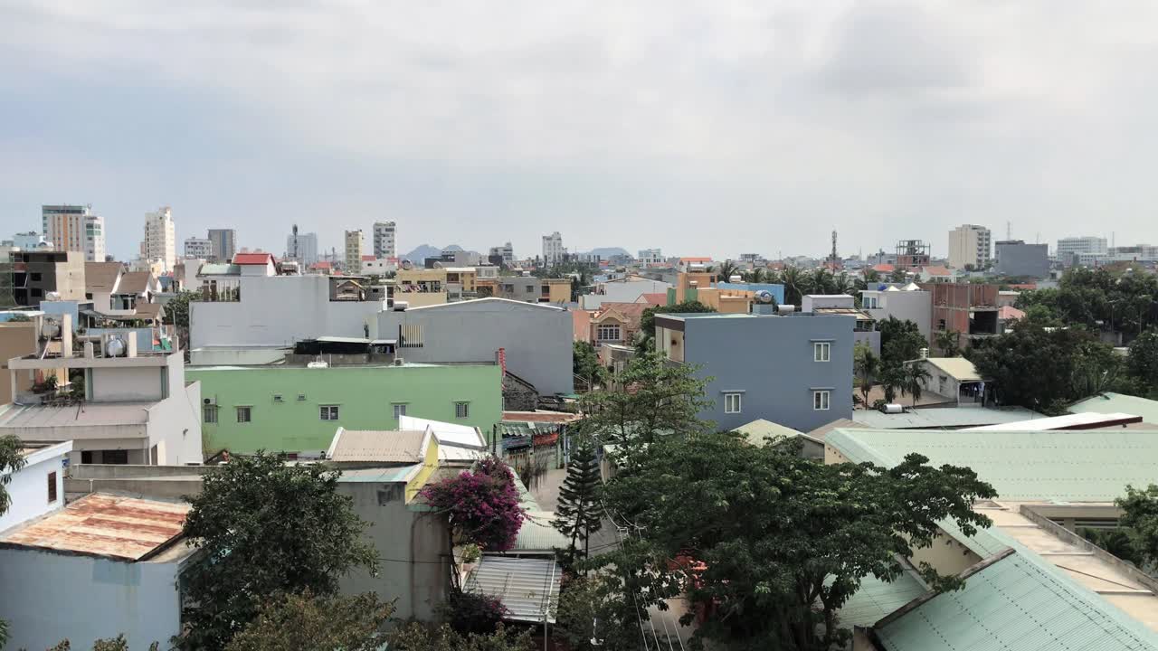 City view of Ngu Hang Son area in Da Nang, Vietnam during the daytime. Sunny weather. Partly cloudy sky. Trees and residential buildings in foreground.