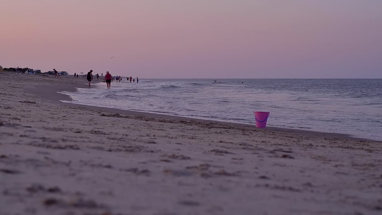일몰 동안 해변을 따라 걷는 관광객