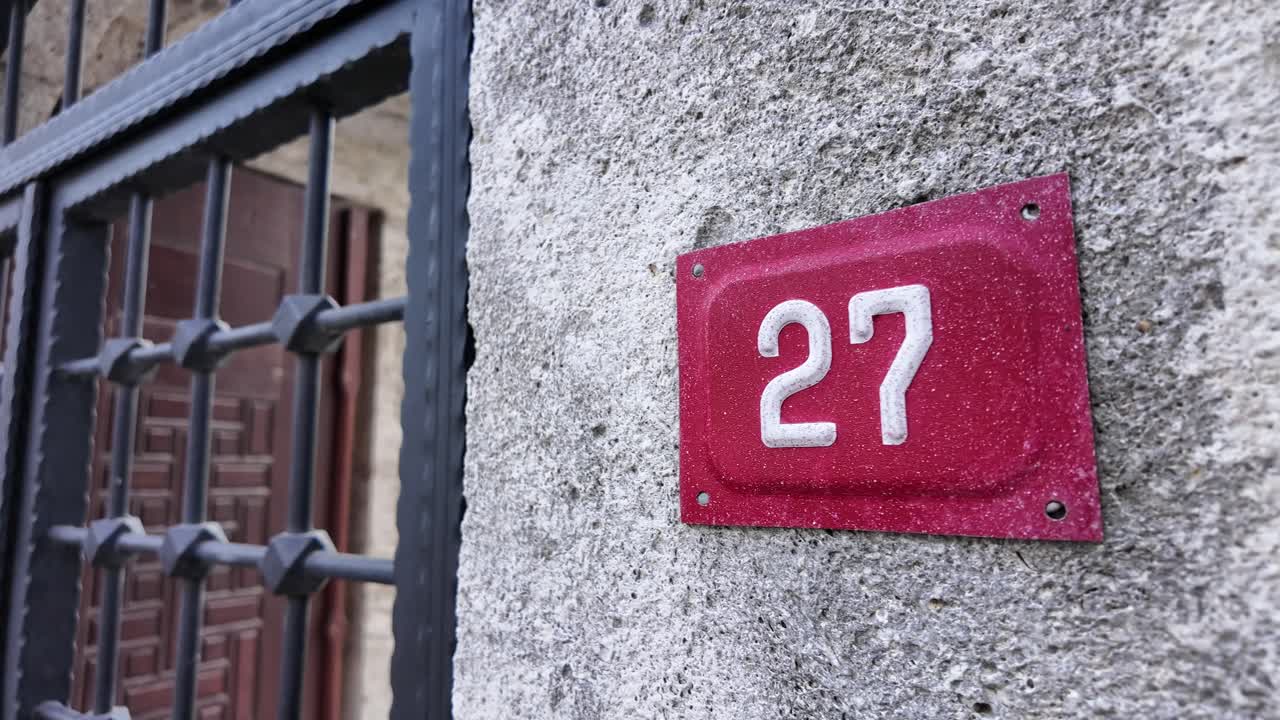 Rødt husnummer 27 på en betonvæg