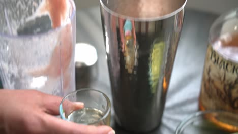 verter licor en una taza de jugo de granada haciendo un cóctel de granada usando jugo de pomegranada fresco y semillas de ron jarabe de lima y ingredientes frescos
