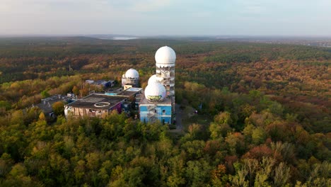 calm aerial view flight drop down drone of radom listening station in
autumn forest at morning sunrise, devil's mountain in woods berlin october 2022