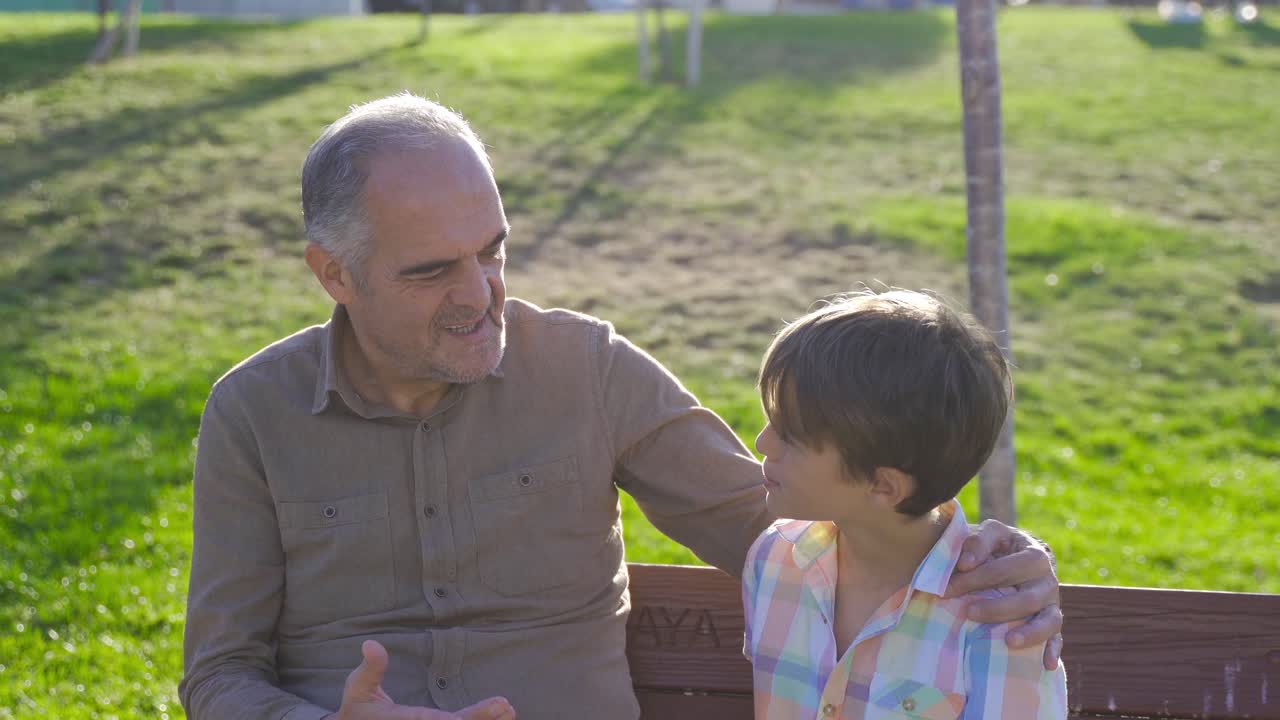 abuelo nieto charlando al aire libre.