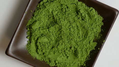 match green tea powder on a brown stone plate rotating in center of frame