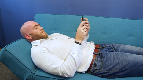 Man-Lying-On-Sofa-And-Using-Mobile