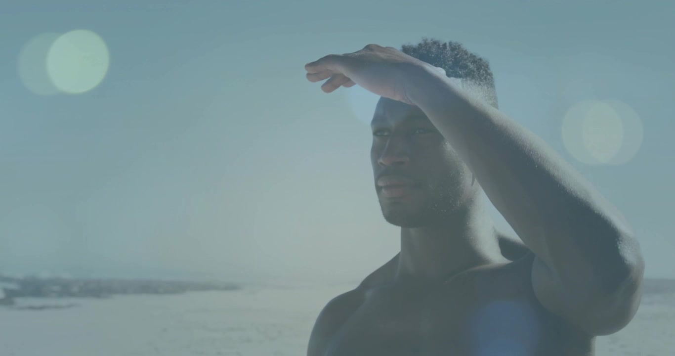 Surfer holding blue board shading eyes from sun scanning waves for surfing with animated lens flare