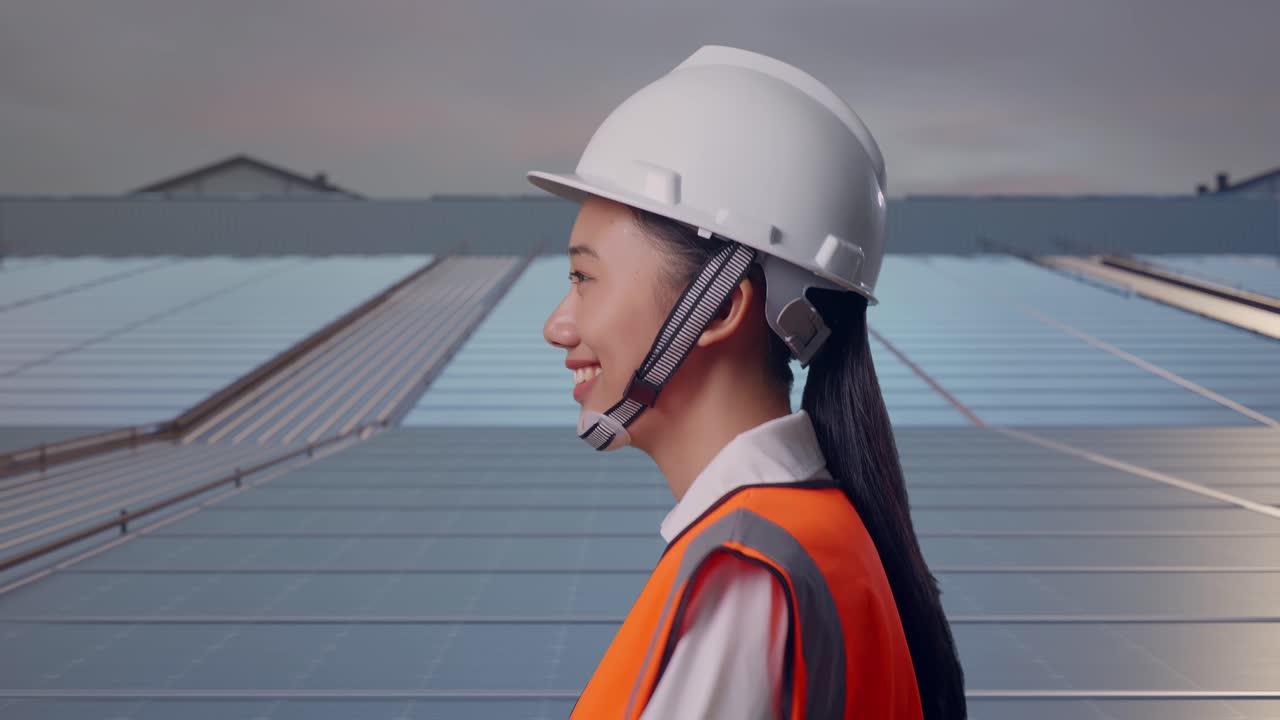 Vista laterale di ingegnere donna asiatica che cammina su un tetto industriale con pannelli solari.