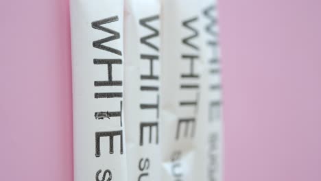 white sugar packets on pink background