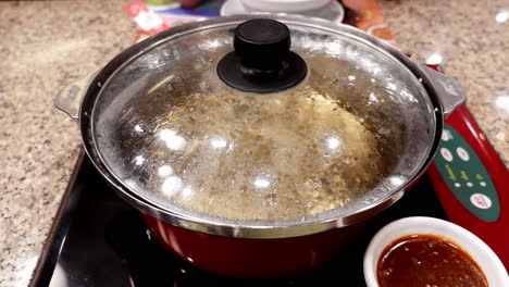 Preparing-boiling-water-for-cooking-in-a-hot-pot-some-Sukiyaki-soup,-a-mixture-of-vegetables-and-different-kinds-of-meat-in-a-restaurant-in-Bangkok,-Thailand