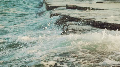 sea waves are washing the rocks near the shore during the day. slow motion