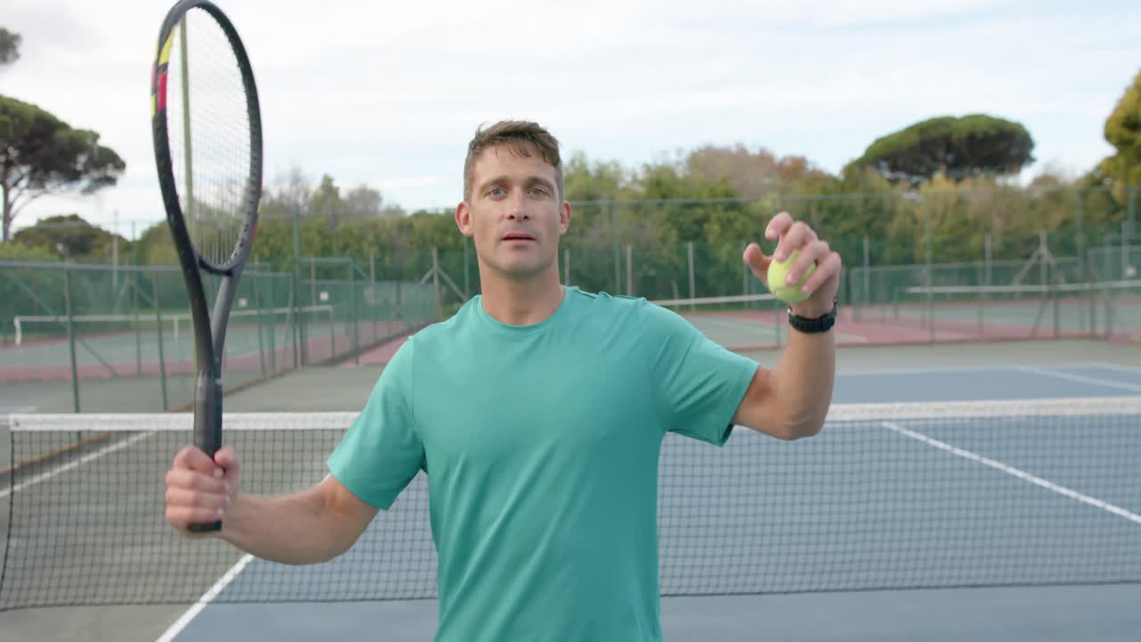 Portrait of serious caucasian male tennis player with racket and ball on outdoor court, slow motion