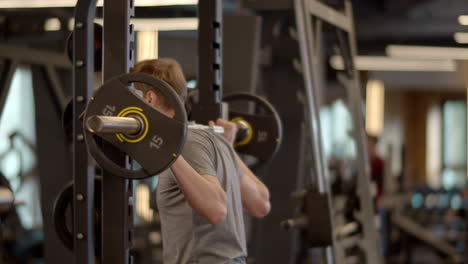 Entrenamiento-Serio-De-Culturista-En-Un-Club-Deportivo.-Deportista-Haciendo-Sentadillas-Con-Barra-En-El-Gimnasio