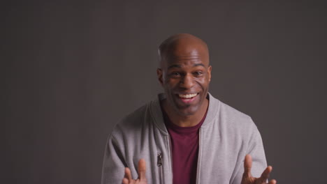 studio portrait of excited mature man celebrating good news standing against grey background