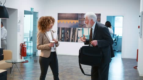 elderly man and woman walking in the large business center hall. colleagues walking in business center