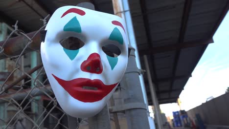 the joker themed clown mask hanging from a chain link fence