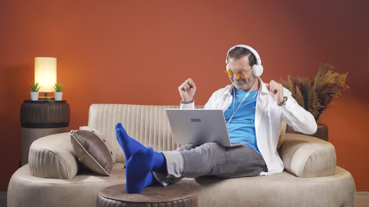 el hombre que mira la computadora portátil está feliz y bailando.