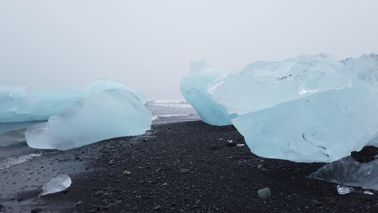 남쪽 아이슬란드의 블랙 다이아몬드 해변에서 씻겨나가는 큰 빙하 얼음 조각들 사이를 걷다