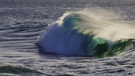 slow motion backdrop background of ocean wave crashing, backlit green with ocean spray erupting