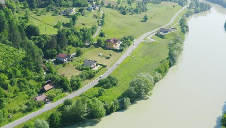 cars driving down a rural road alongside the drava river in slovenj gradec, slovenia