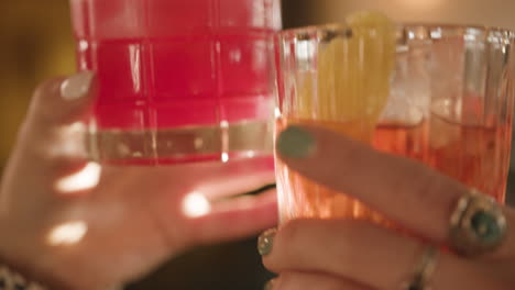 Slow-motion-Feminine-Hands-clink-cocktail-glasses-together-in-sunlit-bar