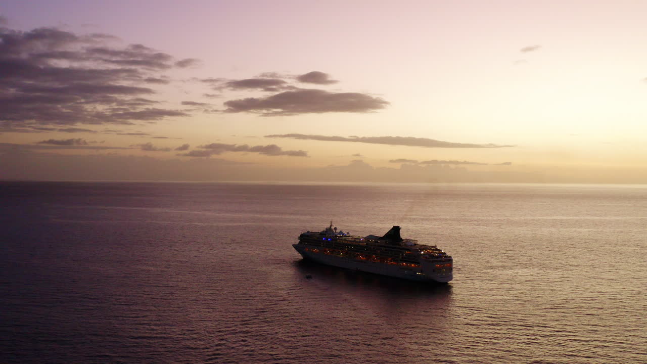 buque de crucero sobrevolado por aviones no tripulados navegando hacia el horizonte en el solsst con silueta, 4k