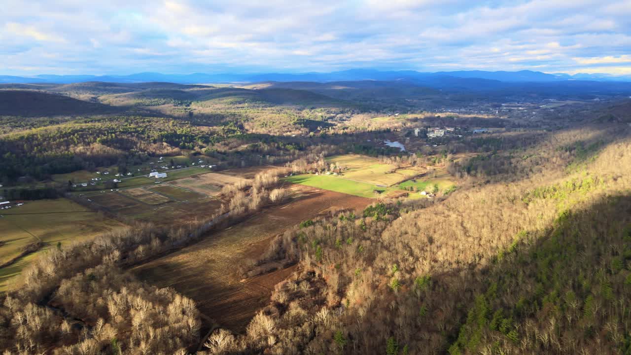 un dron en lo alto de un valle de montaña durante la puesta de sol panoramización lateral con montañas en la distancia durante el otoño en los apalaches del norte con tierras de cultivo debajo