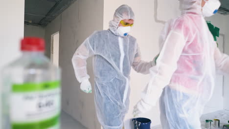 una pareja graciosa en trajes de protección viene bailando a la habitación